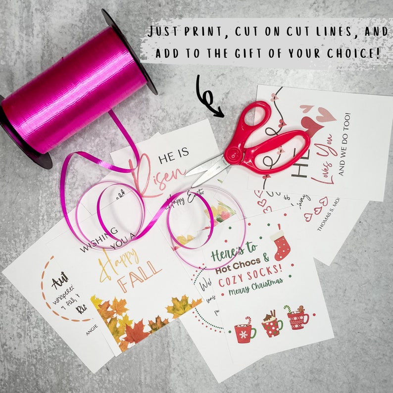 Puede incluir: Cuatro etiquetas de regalo imprimibles con diferentes dise&ntilde;os y textos. Las etiquetas est&aacute;n sobre una superficie gris con una cinta rosa y unas tijeras. El texto en las etiquetas incluye "Wishing you a Happy Fall", "He is Risen", "Here's to Hot Chocs & Cozy Socks! Merry Christmas", y "My Loves You & We Do Too!"