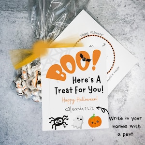 Puede incluir: Una tarjeta blanca con una ilustraci&oacute;n negra de una ara&ntilde;a, un fantasma y una calabaza. La tarjeta dice "BOO! Here's a Treat For You! Happy Halloween! Brenda & Liz" y tiene un espacio para escribir nombres con un bol&iacute;grafo.