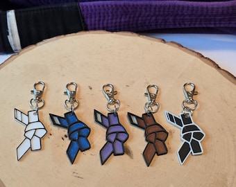 May include: Five keychains with different colored knots, each with a silver clip. The knots are white, blue, purple, brown, and black.