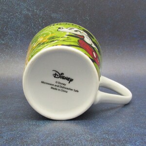 Puede incluir: Taza de cer&aacute;mica blanca con un dise&ntilde;o verde, rojo y amarillo con Mickey Mouse y el texto "Mickey Mouse Clubhouse". La parte inferior de la taza tiene el texto "Disney", "Microwave and Dishwasher Safe", y "Made in China".