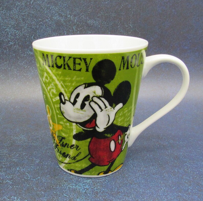 Puede incluir: Una taza de cer&aacute;mica verde con una imagen de dibujos animados de Mickey Mouse. La taza tiene el texto "Mickey Mouse" en la parte delantera y "No Funer Friend" en la parte inferior.