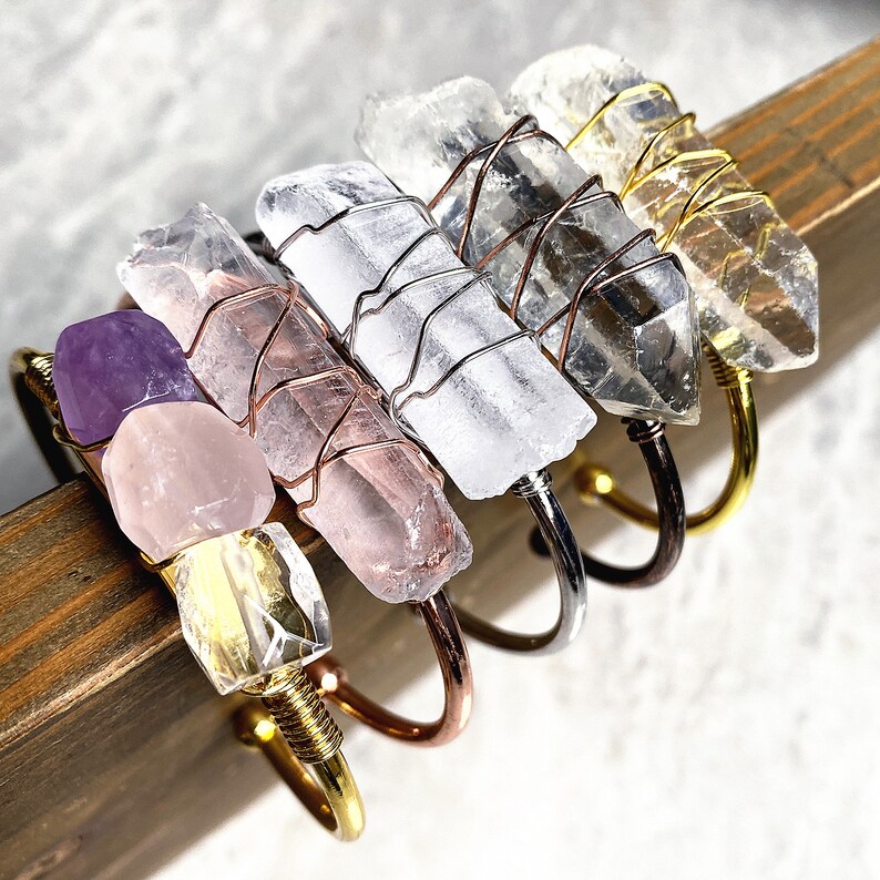 May include: Five crystal bracelets with wire wrapped clear quartz, rose quartz, and amethyst stones. The bracelets are made with gold, silver, and copper wire.