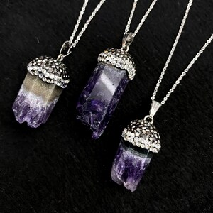 Puede incluir: Tres collares de plata con colgantes de cristal de amatista. Cada colgante est&aacute; rematado con un engaste de plata incrustado con diamantes de imitaci&oacute;n transparentes.