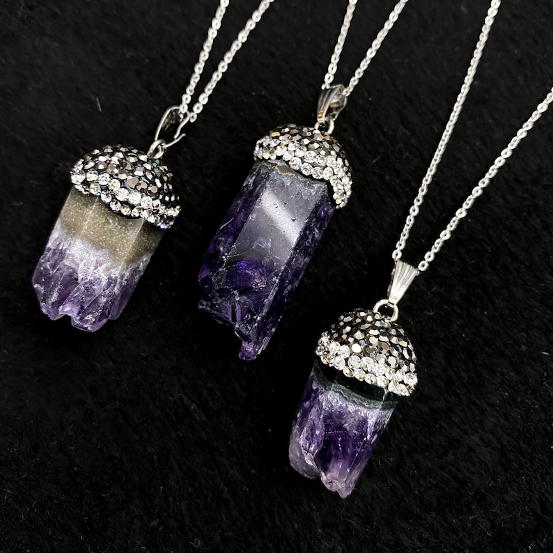 Puede incluir: Tres collares de plata con colgantes de cristal de amatista. Cada colgante est&aacute; rematado con un engaste de plata incrustado con diamantes de imitaci&oacute;n transparentes.