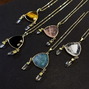 Puede incluir: Cinco collares de oro con colgantes triangulares con diferentes piedras preciosas. Cada colgante tiene dos abalorios de cristal. Las piedras preciosas son ojo de tigre, cuarzo rosa, ónix negro, aventurina y cuarzo transparente.