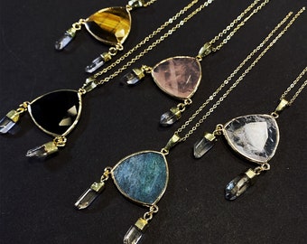 Könnte beinhalten: Fünf goldene Halsketten mit dreieckigen Anhängern, die mit verschiedenen Edelsteinen besetzt sind. Jeder Anhänger hat zwei kristallartige Charms, die daran hängen. Die Edelsteine sind Tigerauge, Rosenquarz, schwarzer Onyx, Aventurin und klarer Quarz.