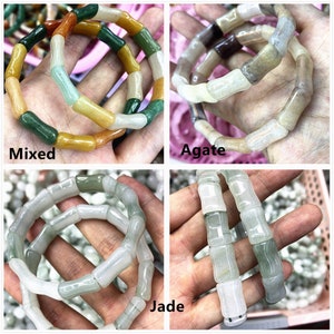 Op de afbeelding: Vier armbanden van gepolijste steen, elk met een bamboe-achtig ontwerp. De armbanden zijn gelabeld met "Mixed", "Agate" en "Jade". De "Mixed" armband heeft een verscheidenheid aan kleuren, waaronder groen, geel en oranje. De "Agate" armband heeft beige en bruine tinten. De "Jade" armband is lichtgroen.