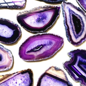 May include: A collection of purple agate slices with varying patterns and shades of purple. The agate slices are smooth and polished, with a natural, organic shape.