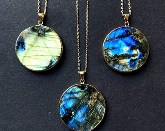 May include: Three gold necklaces with round labradorite stone pendants. The pendants are different shades of blue and green with iridescent shimmer.