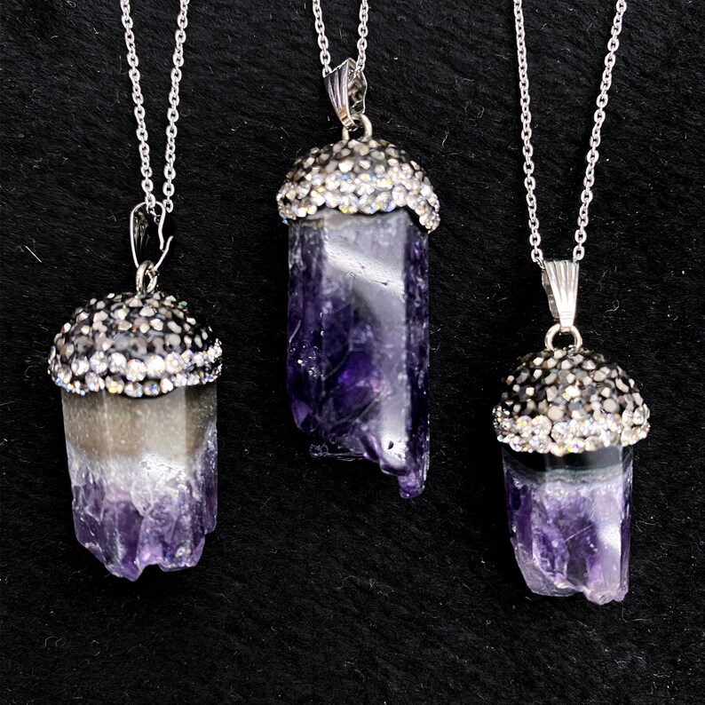 Puede incluir: Tres collares de cadena de plata con colgantes de cristal de amatista. Cada colgante est&aacute; rematado con un bisel de plata engastado con diamantes de imitaci&oacute;n transparentes.