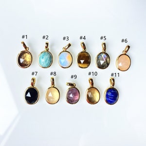 May include: Eleven gold pendants with different coloured gemstones. The pendants are numbered 1 through 11.