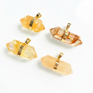 May include: Four gold-wrapped crystal pendants in various shades of yellow and orange. The pendants are shaped like double-ended points and have a gold bail for hanging.