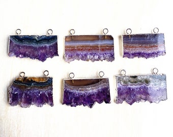 Könnte beinhalten: Sechs Amethyst-Druse-Scheiben mit silberfarbenen Metall-Verbindungsschlaufen. Jede Scheibe zeigt ein einzigartiges Muster aus violettem und weißem Achat.