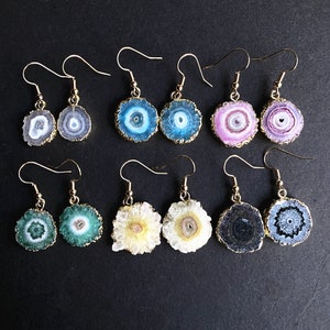 Puede incluir: Conjunto de 10 pares de pendientes de tono dorado con detalles de piedra de &aacute;gata. Cada par presenta un color y un patr&oacute;n de &aacute;gata diferentes, incluidos el azul, el verde, el rosa y el negro.