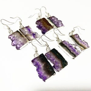 Puede incluir: Cuatro pares de pendientes colgantes de plata con piedras de cristal de amatista. Los cristales son de color morado intenso con un borde natural en bruto. Los pendientes son un accesorio &uacute;nico y elegante.
