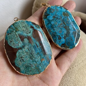 May include: Two oval-shaped agate pendants with gold-toned metal trim. The agate is a mix of brown and teal green with a marbled pattern.