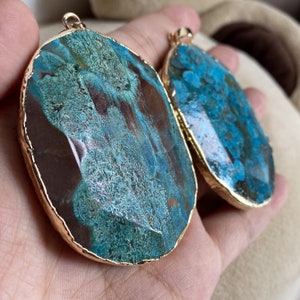 May include: Two agate pendants with gold-plated edges. The pendants are oval-shaped and feature a blue and brown marbled pattern.