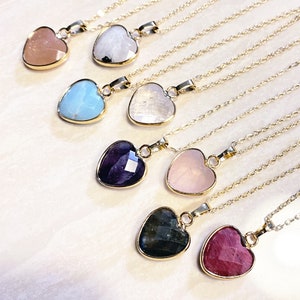 Puede incluir: Ocho colgantes de corazón de oro con piedras preciosas de diferentes colores. Las piedras preciosas son rosa, blanca, azul, púrpura, cuarzo rosa, negra y roja.