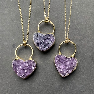 May include: Three gold necklaces with amethyst heart pendants. Each necklace features a delicate chain and a heart-shaped pendant filled with purple amethyst crystals.