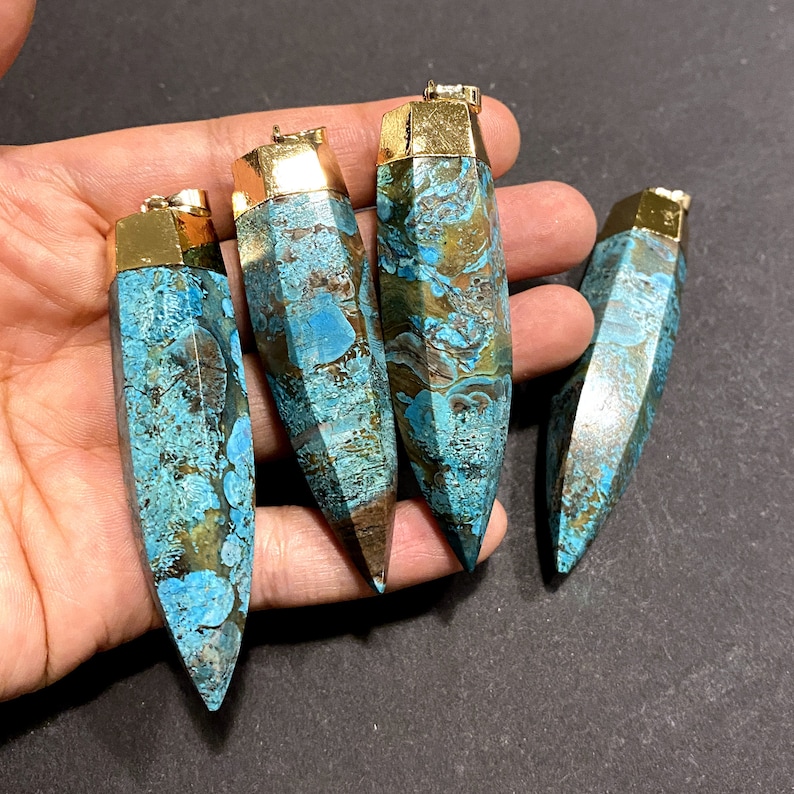 May include: Four turquoise and brown agate gemstone pendants with gold-toned metal caps. The pendants are shaped like long, pointed teardrops.