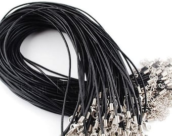 Puede incluir: Un paquete a granel de cordón de cuero negro con cierres de langosta plateados. El cordón está enrollado en espiral y los cierres están dispersos alrededor de la espiral.