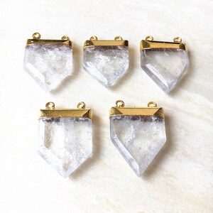 Puede incluir: Cinco colgantes de cristal de cuarzo transparente con marcos de metal dorado. Cada colgante tiene dos agujeros para sujetarlo a un collar o pulsera.