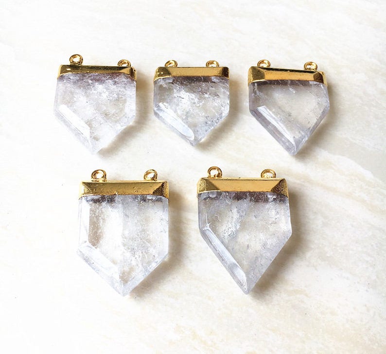 Puede incluir: Cinco colgantes de cristal de cuarzo transparente con marcos de metal dorado. Cada colgante tiene dos agujeros para sujetarlo a un collar o pulsera.