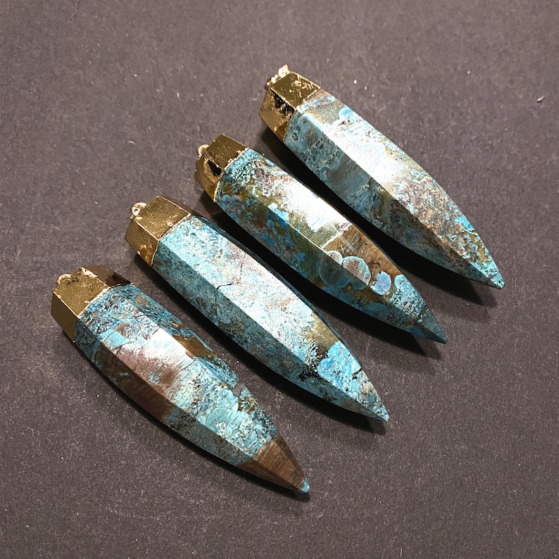 May include: Four turquoise and gold gemstone pendants with a pointed tip. The pendants are made of a natural stone with a marbled pattern.