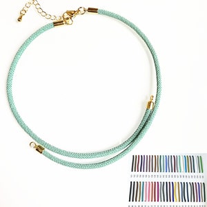 May include: A light green cord necklace with gold clasps. The necklace is shown against a white background. A colour chart of different cord colours is shown below the necklace.
