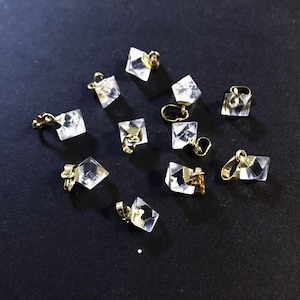 Può includere: Dieci ciondoli a forma di piramide di cristallo trasparente con anelli in metallo dorato. I ciondoli sono disposti su una superficie nera.