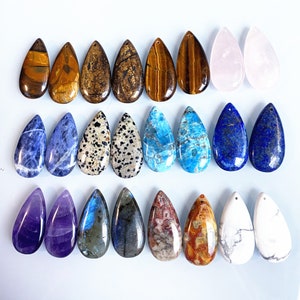 May include: Assortment of 20 teardrop-shaped gemstone pendants in various colours, including blue, green, purple, brown, white, and pink. The pendants are made of natural stones and have a polished finish.