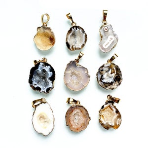 May include: Assortment of eight agate pendant charms with gold-tone settings. Each pendant features a unique, naturally occurring agate pattern with a variety of colors, including white, brown, and gray.