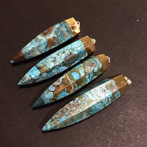 May include: Four turquoise and brown agate gemstone pendants with gold-toned metal caps and loops. The pendants are shaped like long, pointed teardrops.