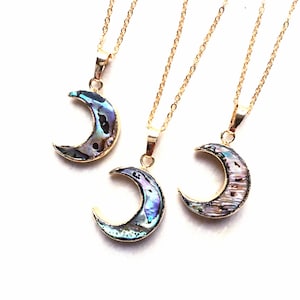 May include: Three gold necklaces with crescent moon pendants made of iridescent abalone shell. The necklaces are on a white background.