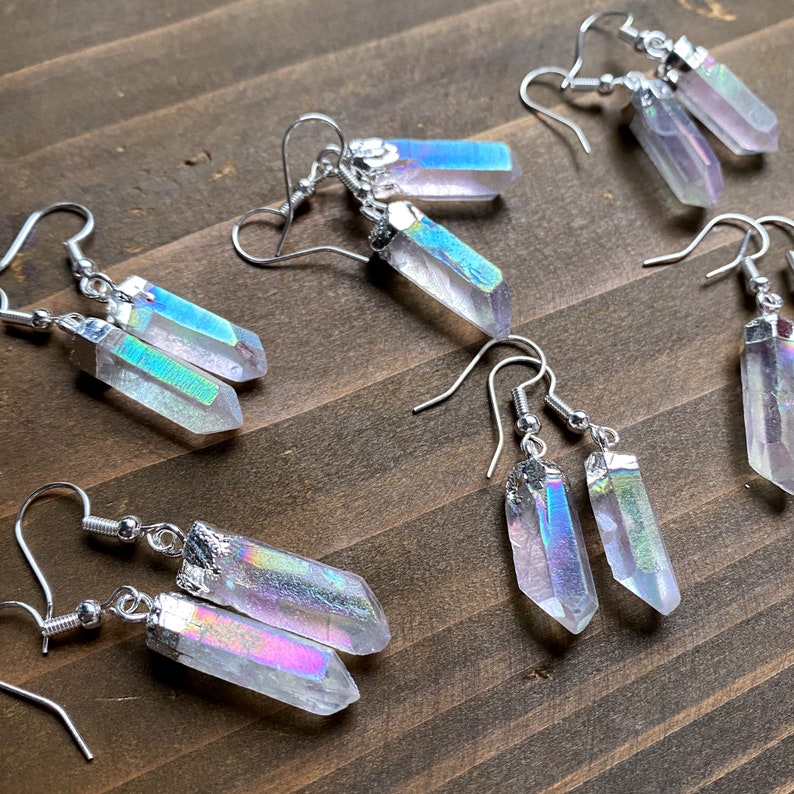 K&ouml;nnte beinhalten: Ein Set mit sechs regenbogenfarbenen Kristallohrringen mit silbernen Haken. Die Kristalle sind klar mit einem Regenbogen-Schimmer.