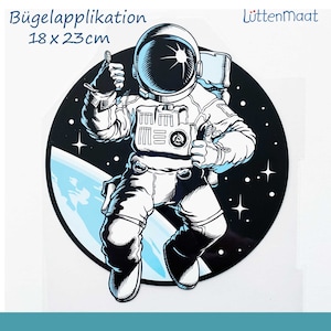 Könnte beinhalten: Eine Schwarzweißillustration eines Astronauten, der einen Daumen nach oben zeigt und mit einem Planeten im Hintergrund im Weltraum schwebt. Der Astronaut trägt einen Raumanzug mit Helm. Das Bild ist ein runder Bügelbild-Patch mit einer Größe von 18 x 23 cm.