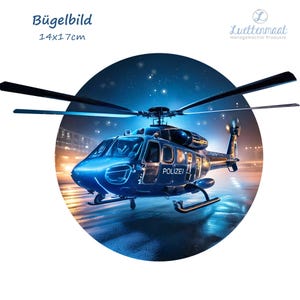 Könnte beinhalten: Ein blauer und weißer Polizeihubschrauber mit dem Schriftzug "POLIZEI" an der Seite, der nachts über eine Stadt fliegt. Der Hubschrauber wird von den Lichtern der Stadt unten beleuchtet. Das Bild ist ein Bügelbild von 14x17 cm.