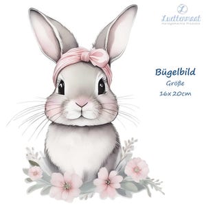 Könnte beinhalten: Ein süßes graues Kaninchen mit rosa Ohren und einem rosa Schleifenband. Das Kaninchen ist von rosa Blumen und grünen Blättern umgeben. Das Bild ist ein Bügelbild für Kleidung, mit einer Größe von 16x20 cm.
