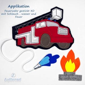 Könnte beinhalten: Ein Filz-Applikation mit einem roten Feuerwehrauto mit weißen und grauen Akzenten, einem blauen Wasserstrahl und einer orange-gelben Flamme. Das Design enthält den Text "Applikation" und andere deutsche Texte.