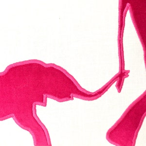 Op de afbeelding: Een wit kussen met een roze geborduurd ontwerp van twee olifanten. De grotere olifant staat en de kleinere olifant loopt naar de grotere olifant.