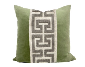 May include: A square decorative pillow in a soft green hue. The center panel features a geometric pattern in shades of gray and off-white. The pillow has a plush, velvety texture, perfect for adding a touch of elegance to any room.