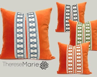 Op de afbeelding: Vier decoratieve kussens met oranje fluweel en geometrische versiering. De versiering is in verschillende kleuren, waaronder blauw, groen en wit.