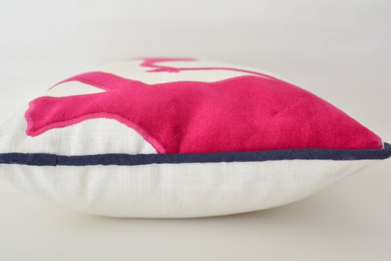 Op de afbeelding: Een wit kussen met een roze vilt applique van een flamingo. Het kussen heeft een donkerblauwe rand.