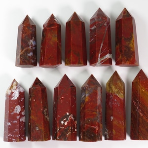May include: A collection of 15 red, brown, and white jasper crystal points. The points are arranged in two rows, with the points in the top row slightly offset from the points in the bottom row.