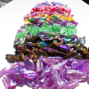 May include: A rainbow assortment of iridescent crystal points. The crystals are arranged in a rainbow order, from red to purple. The crystals are all different sizes and shapes.
