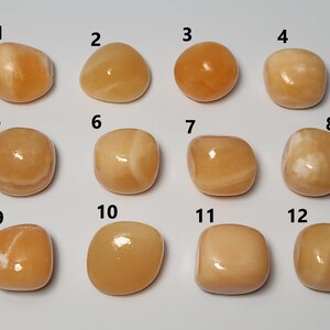 May include: Twelve smooth, polished orange calcite stones, numbered 1 through 12, arranged in rows of four. Each stone has a unique pattern of white veins.