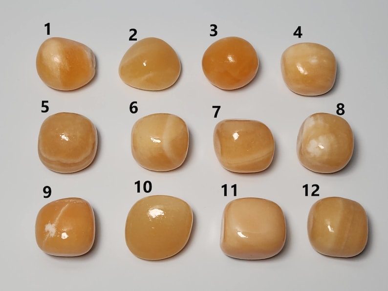 May include: Twelve smooth, polished orange calcite stones, numbered 1 through 12, arranged in rows of four. Each stone has a unique pattern of white veins.