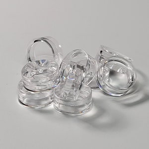 May include: A group of clear plastic rings, stacked and overlapping. The rings are smooth and translucent, with a slightly rounded edge.