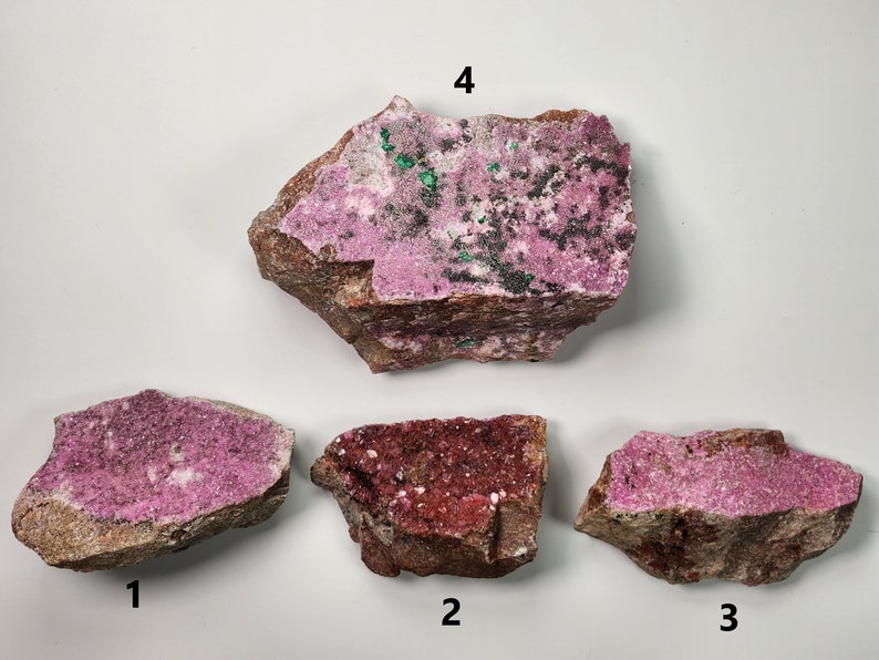 May include: Four pieces of pink, red, and green cobalt ore. The ore is rough and has a crystalline texture. The pieces are labeled 1 through 4.