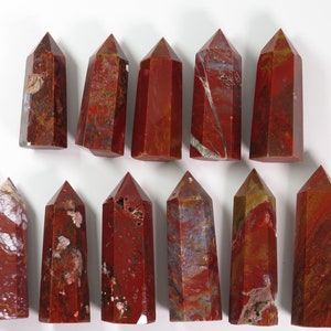 May include: Twelve red jasper crystal points with varying shades of red, brown, and white. The points are all approximately the same size and shape.